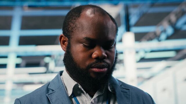 Server room admin using tablet app to enhance operational effectiveness of hardware. African american man in data center using device to monitor infrastructure rackmounts, camera B