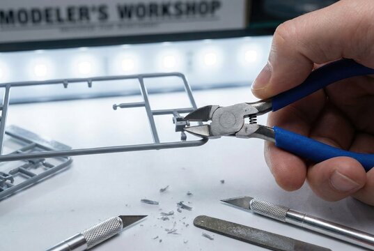 Close up of a hand using side cutters to remove a plastic part from a model kit sprue
