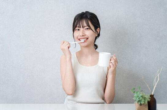 A young Asian woman brushing her teeth (toothbrushing, oral care, dental care)