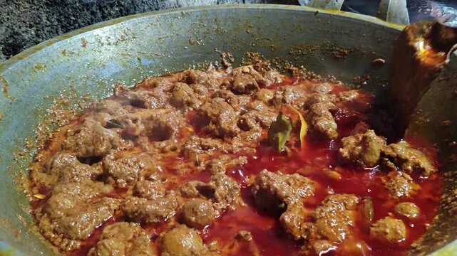 Final stage of rendang cooking, thick brown rich texture, slow-cooked Indonesian beef dish ready to serve, showcasing authentic traditional culinary process.