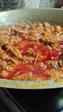 Final stage of rendang cooking, thick brown rich texture, slow-cooked Indonesian beef dish ready to serve, showcasing authentic traditional culinary process.