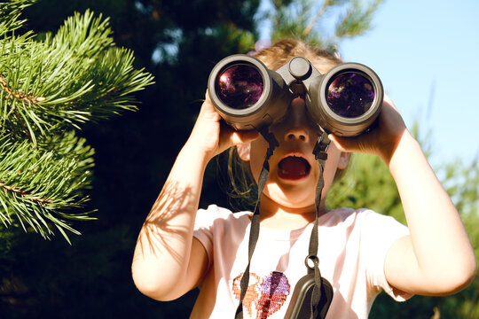Young preschool girl using binoculars in the forest. Exploring the world. Outdoors activities. Bird watching. Adventure