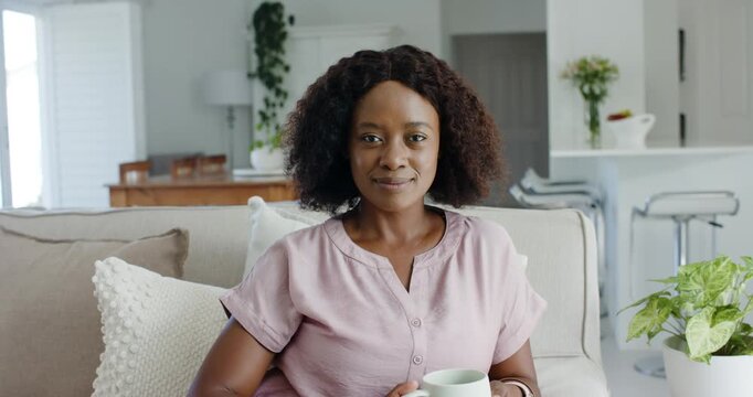 Woman sitting on sofa lifting mug to camera and smiling, sharing routine with animated health stats