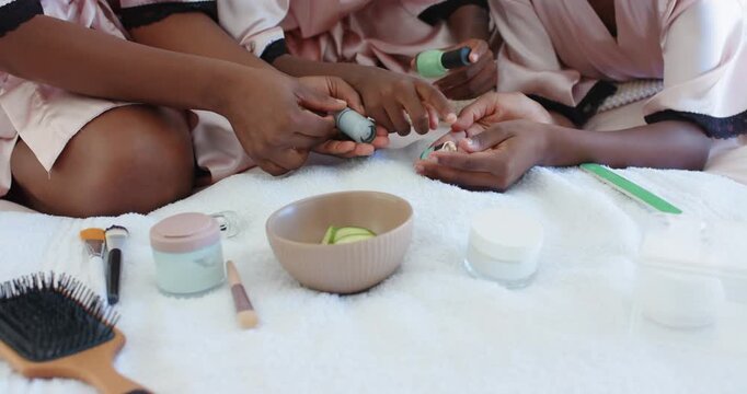 Mother guiding child's hands to open turquoise bottle, applying manicure on white bedspread