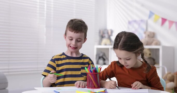 Cute little kids drawing with felt tip pens at white table indoors