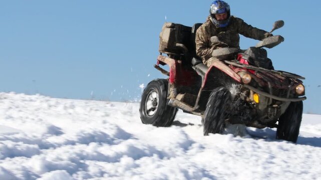 Man drifting quad bike on snow in mountains