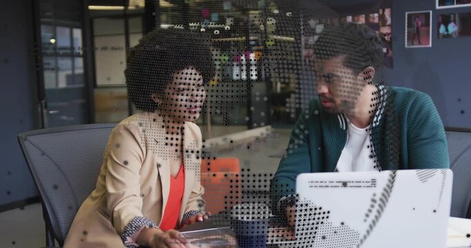 Woman pointing at portfolio with dotted overlay causing man typing on laptop making business edits