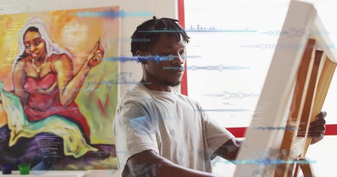 Male painter placing canvas on easel causing blue data overlays across torso and face refining art