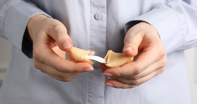 Woman breaking yummy fortune cookie with prediction, closeup