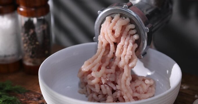 Man making minced meat with grinder at wooden table, closeup. Camera moving in