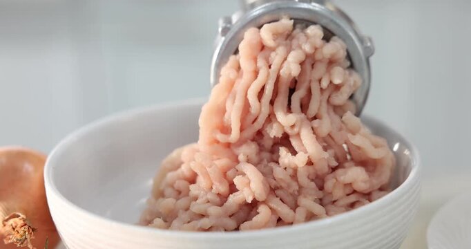 Woman making minced meat with grinder at table indoors, closeup