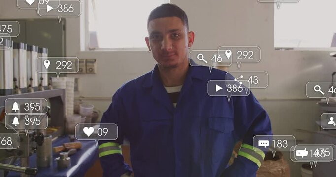 Notifications popping, worker in blue coverall reacting to online likes while standing by workbench
