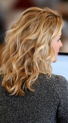 Naklejka premium Woman with Beautiful Curly Blonde Hair Sitting at Desk in Office