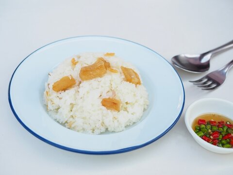 Pork cracklings with fried garlic, served with rice and fish sauce dip, are placed on a white background. They are golden yellow, look appetizing, and are very crispy and delicious.