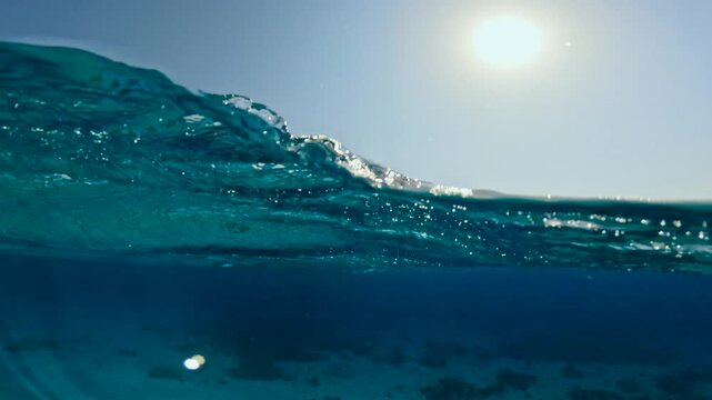 Slow motion half underwater view of rough sea waves and tour boats anchored near coral reef