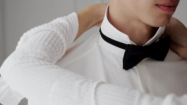Close up of woman adjusting black bow tie on white shirt preparing formal outfit for work event or hospitality service.