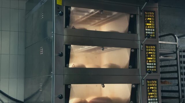 Fresh artisan bread baking inside a professional oven in a small bakery. Golden loaves rise and develop a crisp crust during the traditional baking process in a warm bakery environment