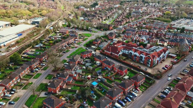 aerial drone landscape shot over Romsey, Hampshire, England Town village in spring sunset surrounded by nature trees and fields with golden warm light above. Calm quiet roads and paths below