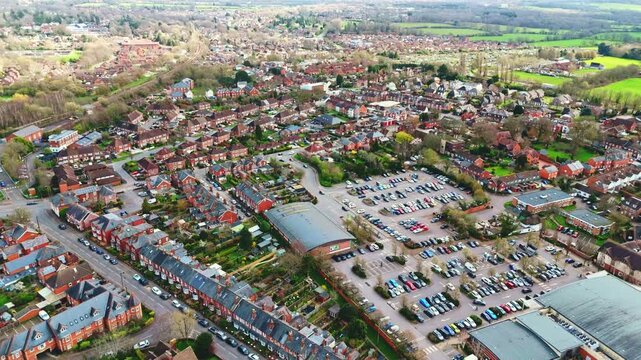 aerial drone landscape shot over Romsey, Hampshire, England Town village in spring sunset surrounded by nature trees and fields with golden warm light above. Calm quiet roads and paths below