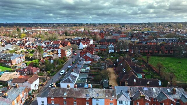 aerial drone landscape shot over Romsey, Hampshire, England Town village in spring sunset surrounded by nature trees and fields with golden warm light above. Calm quiet roads and paths below