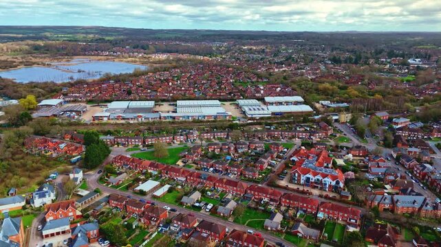 aerial drone landscape shot over Romsey, Hampshire, England Town village in spring sunset surrounded by nature trees and fields with golden warm light above. Calm quiet roads and paths below