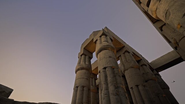 The Luxor Temple in Luxor, Egypt, during a vibrant sunset. The clip highlights the Great Colonnade of Amenhotep III, featuring two rows of seven massive papyrus-style columns that reach approximately