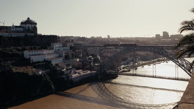 The iconic double-deck iron arch of Ponte Lu&iacute;s I spans the Douro river in Porto, Portugal, with the historic Serra do Pilar monastery crowning the hilltop above Vila Nova de Gaia on a clear winter day