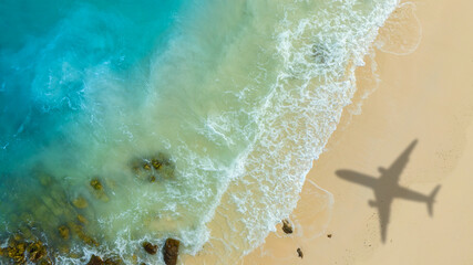 Aerial view of shadow passenger plane silhouette and sandy beach blue sea with waves at sea beach summer vacation sea travel concept	