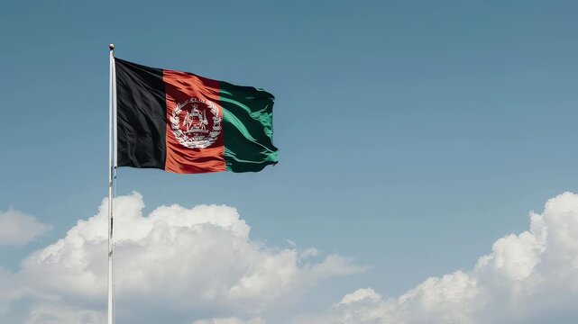 The national flag of Afghanistan waving proudly on a flagpole against a clear blue sky with scattered white clouds, showcasing its distinctive black, red, and green tricolor design