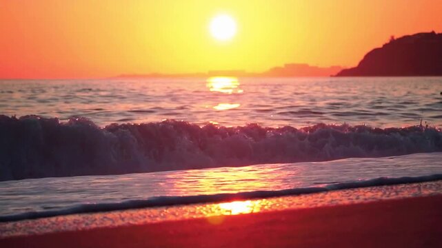 Captivating sunset over the ocean, with gentle waves lapping at the sandy shore under a golden sky. The sun dips low on the horizon, casting warm reflections on the water and foam.