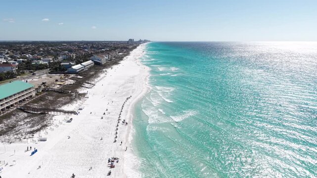 Panoramic aerial fly of bright turquoise Gulf ocean water along white sandy beach, 30A, Florida, USA