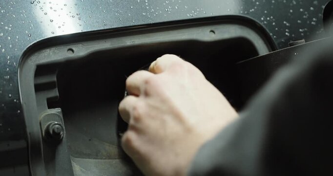 Close-up of a person opening the diesel fuel cap of a car before refueling.