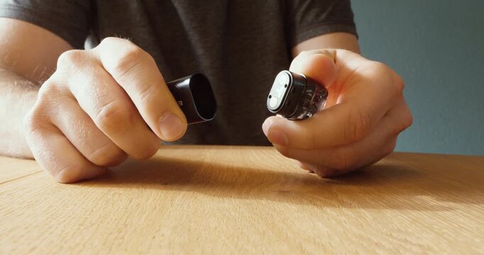 Close-up of a person inserting a pod cartridge into a vape device before use.
