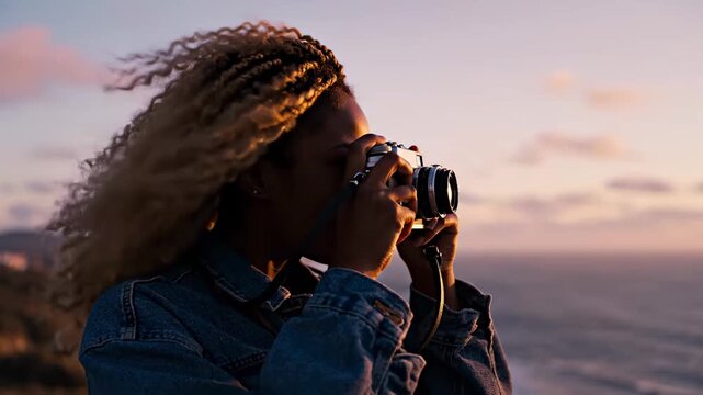Capturing the Golden Hour, Young Woman Taking Photos with Vintage Camera at Sunset by the Ocean for Travel and Lifestyle Content.