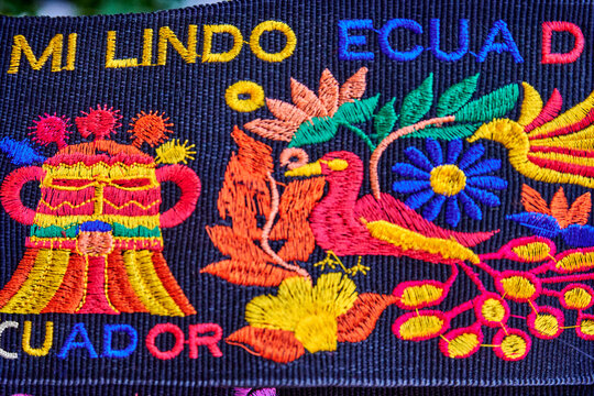 Decorative embroidered ribbon featuring vibrant Ecuadorian symbols, including flowers and birds, showcasing intricate craftsmanship and cultural heritage in bright colors