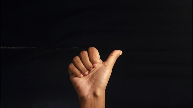 Close-up of a human hand showing different gestures against a black background. The isolated composition highlights communication, body language, and symbolic meaning of hand signs. Ideal for concepts