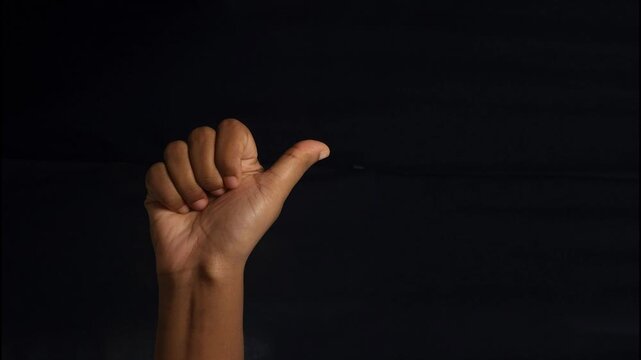 Close-up of a human hand showing different gestures against a black background. The isolated composition highlights communication, body language, and symbolic meaning of hand signs. Ideal for concepts