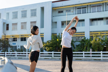 Obraz premium Two Sporty Asian woman stretching wawrmup at stadium