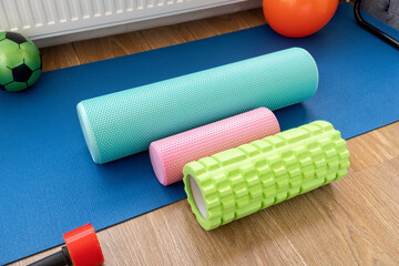 Fototapeta premium Different types of foam rollers and equipment on blue exercise mat in gym area at home