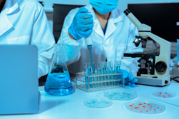 Fototapeta premium Team of biochemical research scientists working with a microscope for vaccine development
