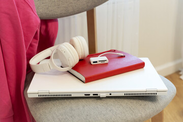 Fototapeta premium A laptop with a notebook and headphones is lying on a chair