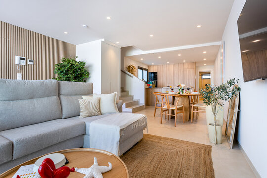 Modern open plan living room and dining area with kitchen, sofa and minimalist contemporary interior design