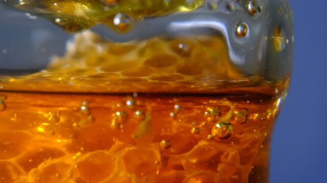 Close up super macro shot scene golden honey liquid bubbles in glass ,honey comb macro product studio shot with the bubble fluid texture