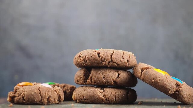 Close up of hand taking chocolate chip cookie from stack on dark background during daytime in kitchen