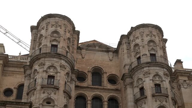 Wide view of Malaga Cathedral highlighting its towering stone structure detailed facade and historic architectural presence within the surrounding square