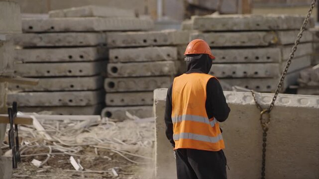A slinger worker looks at the lifting of a concrete slab