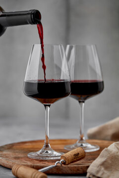 Pouring red wine into glass with bottle in background