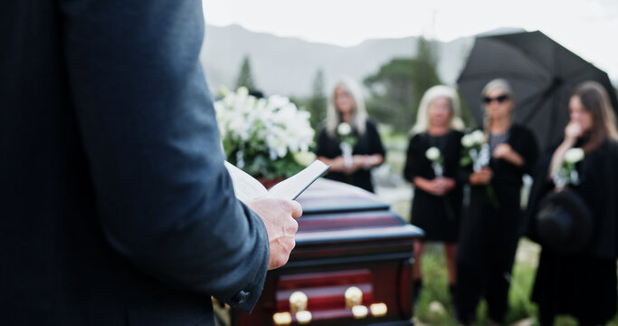 Person, hands and funeral with holy bible or coffin for memorial service, prayer or worship of god. Family, people or christianity with book, religion or faith at graveyard or cemetery for death