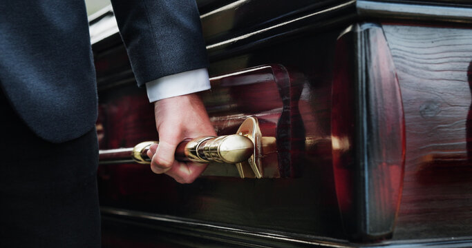 Hands, handle and man with coffin for funeral, sad and compassion for death ceremony. Closeup, person and bereavement with casket, memorial service or support for loss, religion or respect with grief