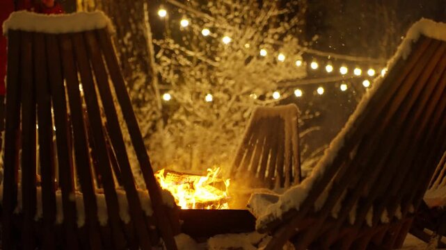 Snow Dusted Chairs Near Fire Pit Frame Roaring Flame And Glowing String Lights, Ember Sparks And Warm Reflections On Wood Lounger Edges, Intimate Outdoor Lounge Setting On Cabin Terrace, Perfect